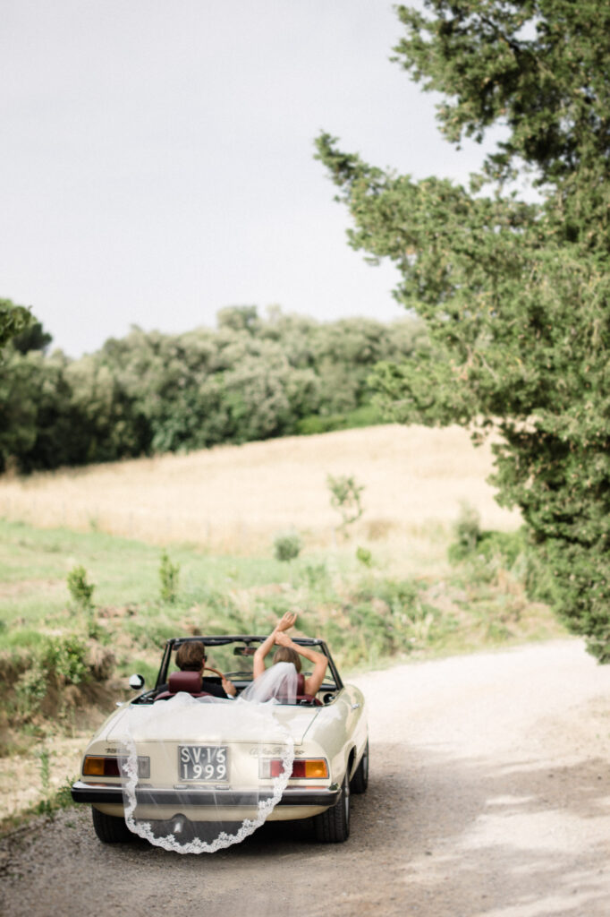Newlywed couple beside a vintage car at a destination wedding in Spain