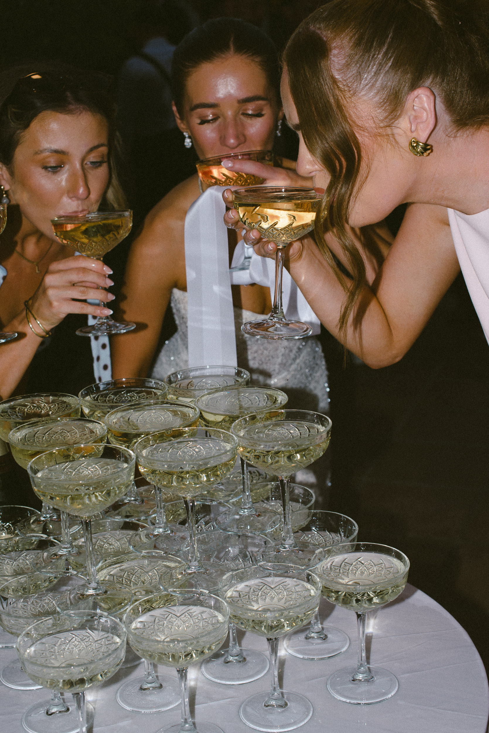 Bride and friends drinking champagne from a champagne tower at a wedding in Spain